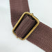 A close up image of the hardware used to adjust the Stella Bag Strap. a brass adjuster is used on brown strapping.